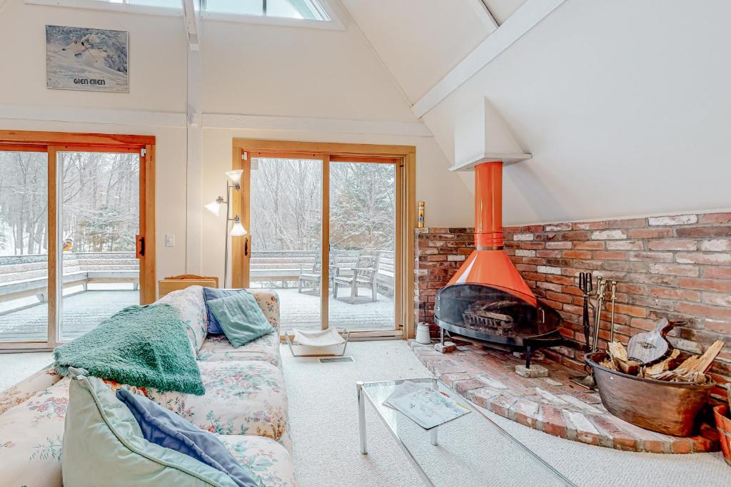 uma sala de estar com um sofá e uma lareira de tijolos em Mt Ellen Ski Chalet em Waitsfield