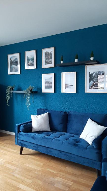 Chevry的住宿－A 6 mns de la station de ski Crozet, proche Genève，客厅里设有蓝色的沙发,拥有蓝色的墙壁