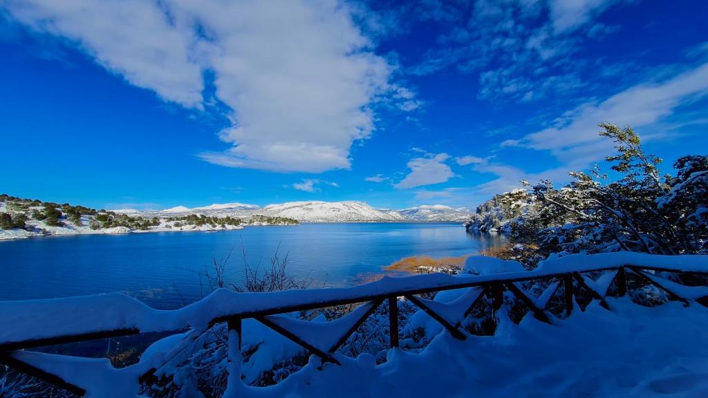 a snowy view of a lake with mountains in the background at Cabañas Aucaman in Villa Pehuenia