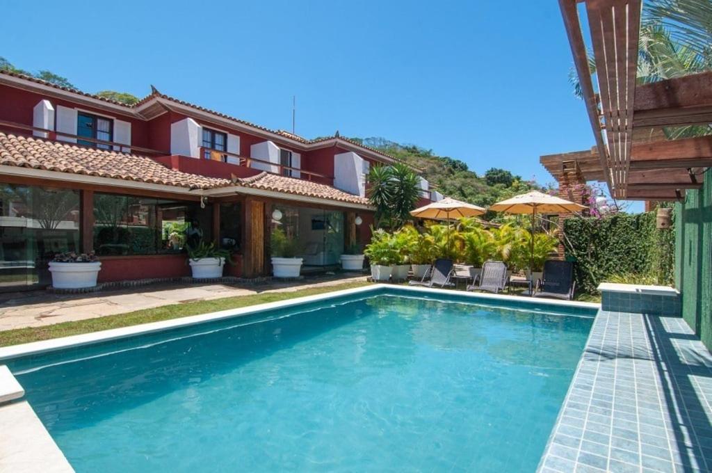 a swimming pool in front of a house at Riviera Búzios Hotel in Búzios