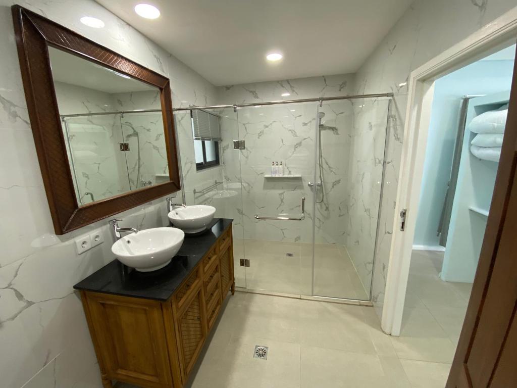 a bathroom with two sinks and a shower with a mirror at Nasara Resort Mentawai in Tua Pejat