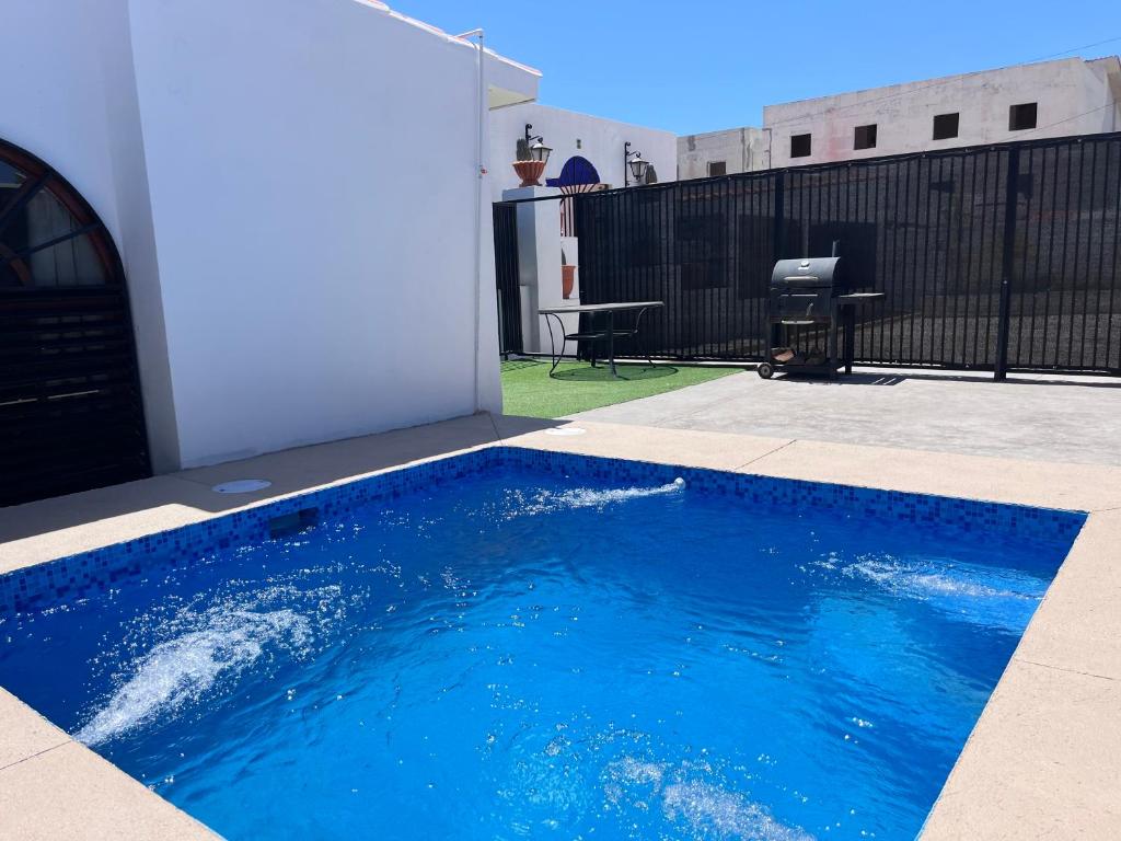 a blue swimming pool in a yard with a fence at Casa Manila ALBERCA TERRAZA Y ACCESO A PLAYA in Bahía Kino