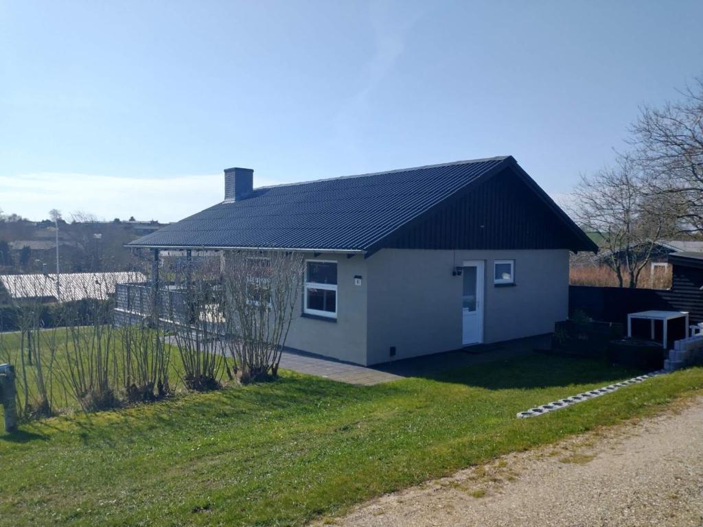 ein kleines weißes Haus mit schwarzem Dach in der Unterkunft Holiday home Roslev XXX in Roslev
