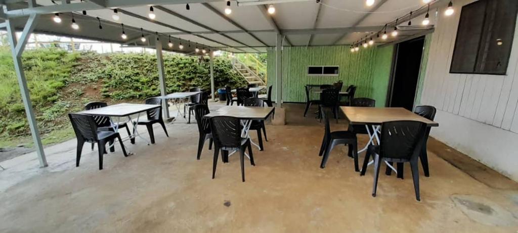 a restaurant with tables and chairs and a green wall at Wind Valley Farmstay in Kampong Kundassan