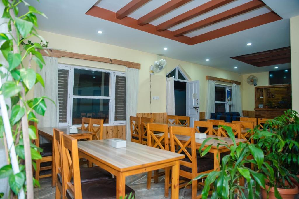 Un comedor con mesas y sillas de madera. en Hotel Olympus Pokhara, en Pokhara