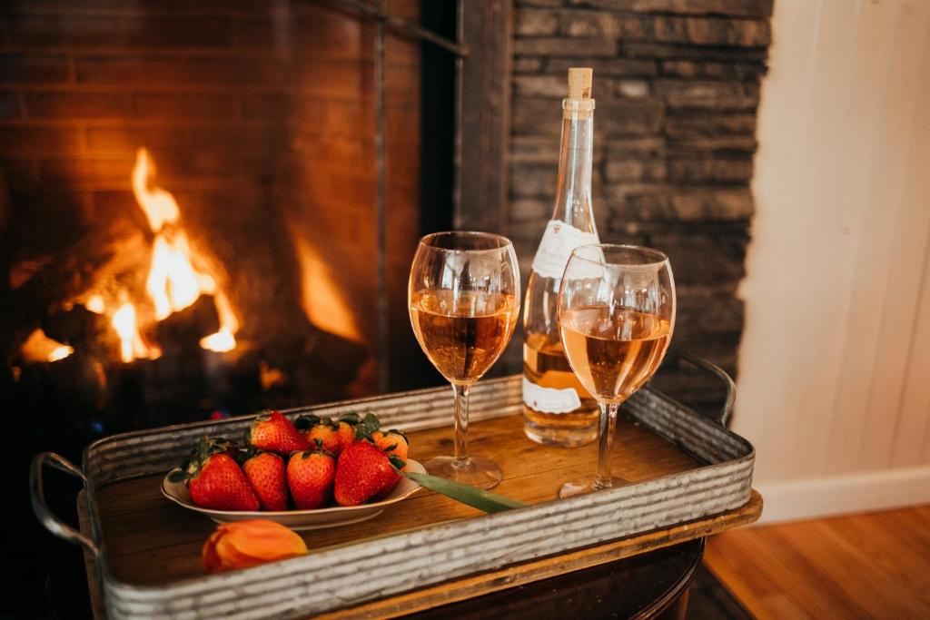 two glasses of wine and a bowl of strawberries in front of a fireplace at Taylor Creek Lodge in Gold Beach