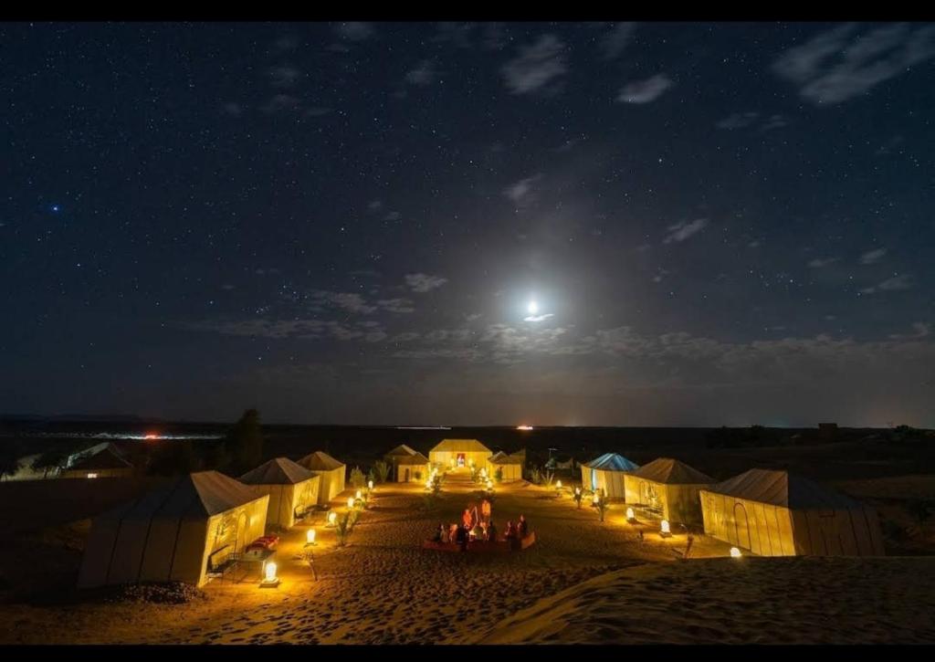 grupa ludzi stojących na polu w nocy w obiekcie Dune Merzouga Camp w mieście Merzouga