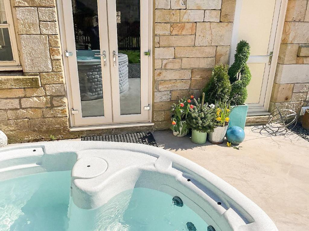 a hot tub in front of a house at Kielder Cottage - E3533 in Kielder