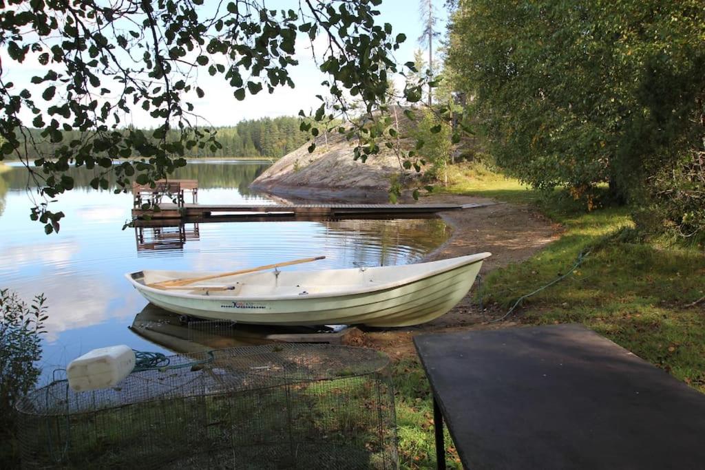 un barco sentado en el agua junto a un muelle en Villa Hyppykallio, LaatuLomat, en Juva