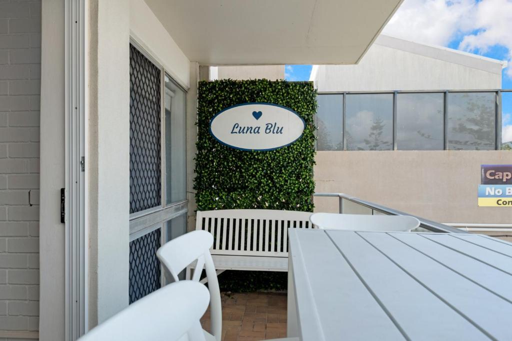 a balcony with a table and chairs in front of a building at Luna Blu - Private Apartment Yeppoon in Yeppoon