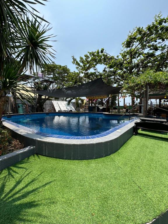 a swimming pool with a green lawn around it at Generosa Beach Club in Bauang