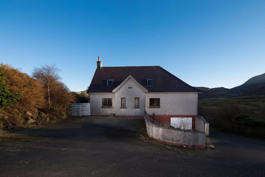 a white house with a black roof and a driveway at Tigh Chailein in Tarbert