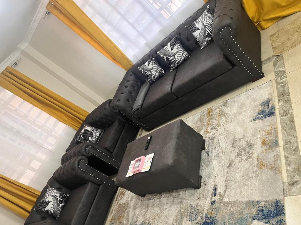 a black couch sitting in a living room next to a window at B’s homely in Ruiru