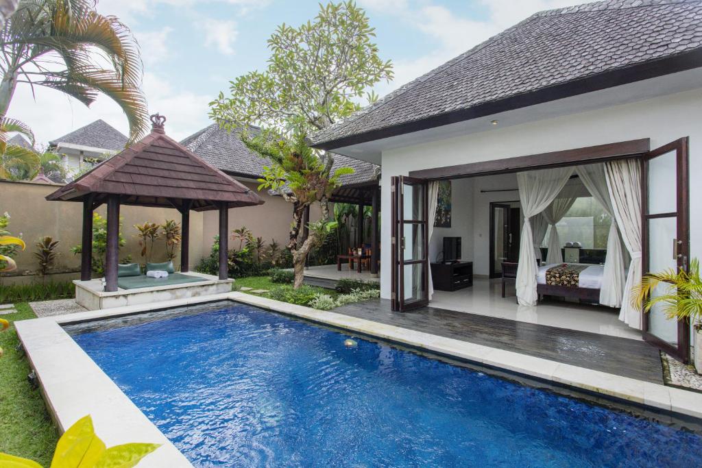 a villa with a swimming pool and a bedroom at The Bidadari Villas and Spa Umalas - CHSE Certified in Canggu