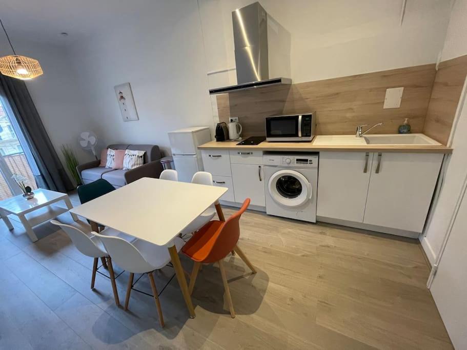 eine Küche und ein Wohnzimmer mit einem Tisch und einer Mikrowelle in der Unterkunft Cosy T3 proche Gare et Polygone in Béziers