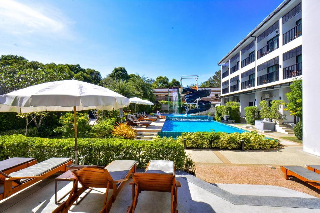 a hotel with a pool and chairs and an umbrella at Aonang Viva Resort - SHA Plus in Ao Nang Beach