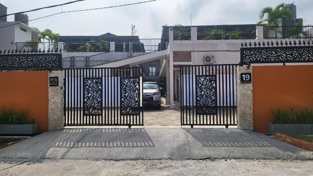 um portão em frente a uma casa com um carro em Rumah Tropis - Lantai 1, single room em Parit