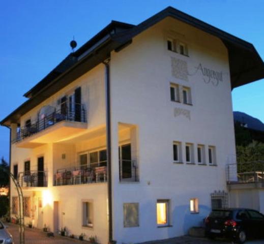 a white building with a car parked in front of it at Pension Angergut in Cermes