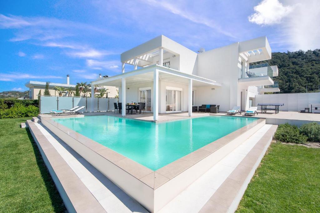 a large white house with a large swimming pool at Villa Odysseas in Ialysos