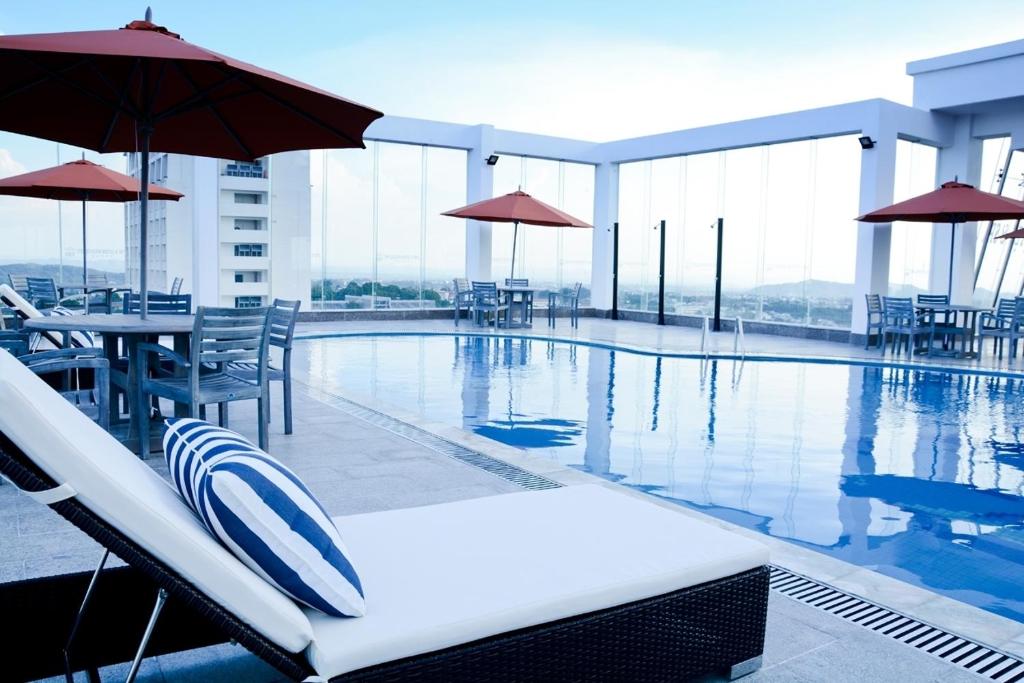 a swimming pool with chairs and tables on a building at Hai Ba Trung Hotel & Spa in Buon Ma Thuot