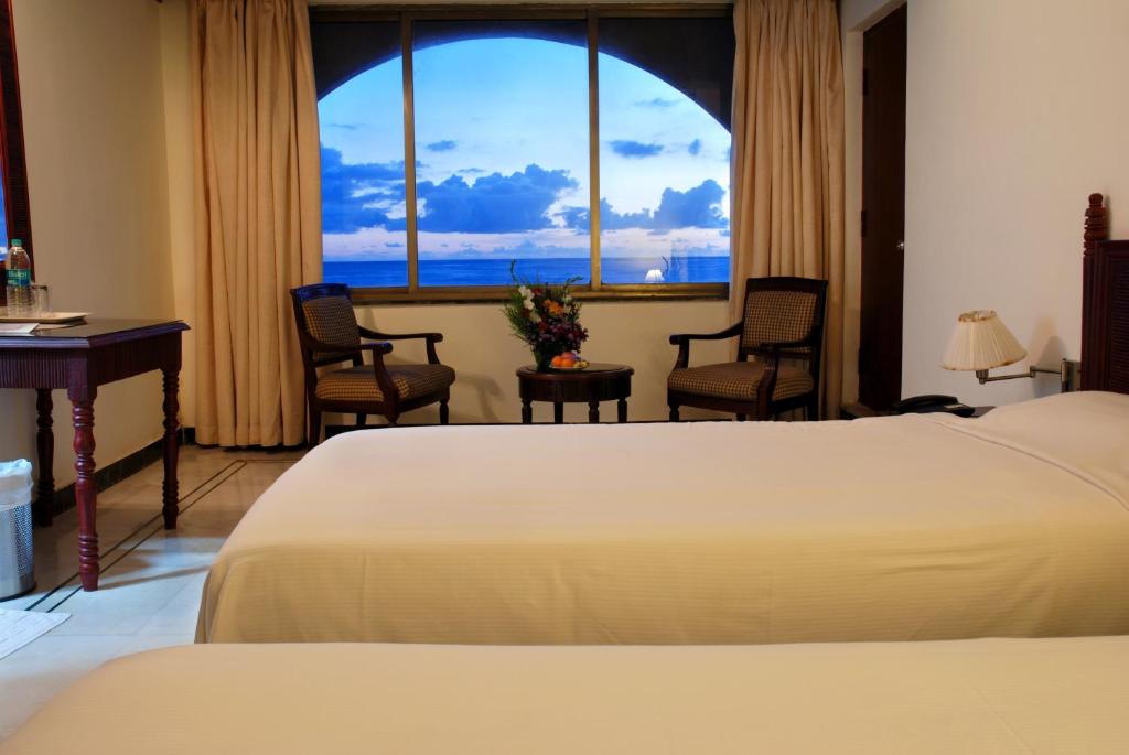 a hotel room with a bed and a desk and a window at Paradise Isle Beach Resort in Udupi