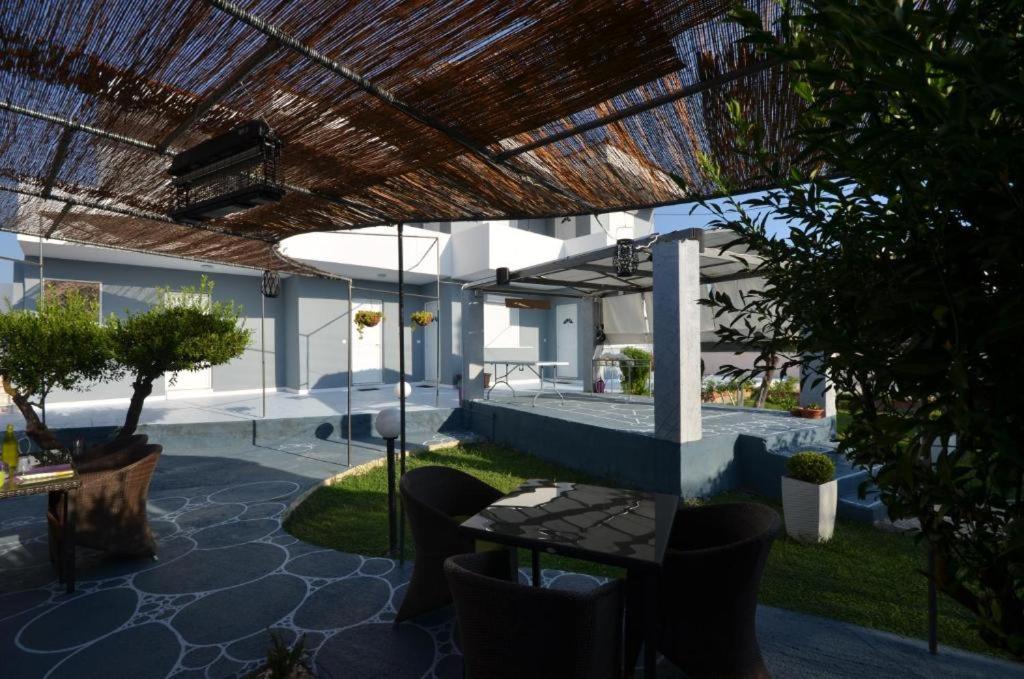 un patio con mesa y sillas bajo un techo en Karmik Concept Apartments, en Afantou