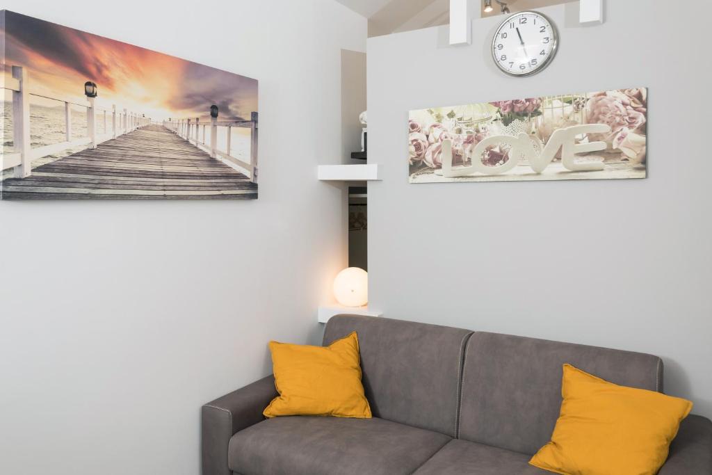 ein Wohnzimmer mit einem Sofa und einer Uhr an der Wand in der Unterkunft Monolocale Glicine in Schisò