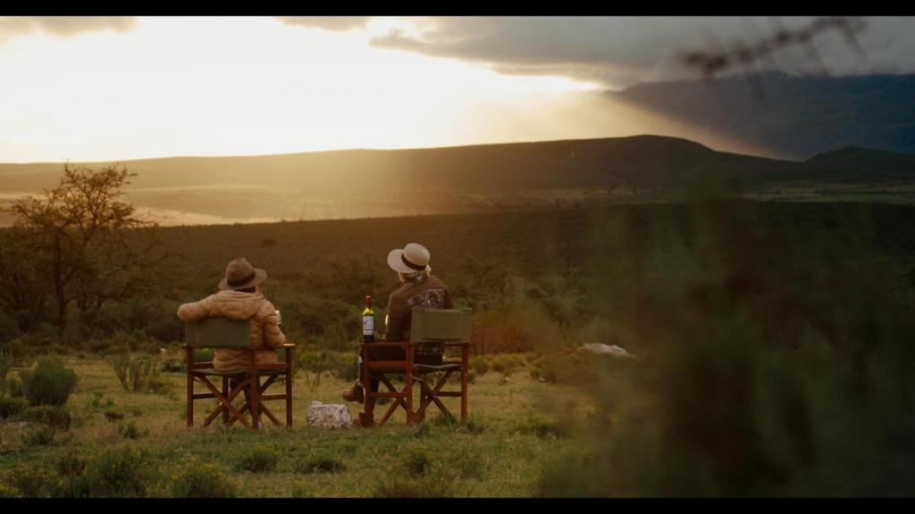 two people sitting in chairs watching the sunset at Wildehondekloof Game Lodge in Matjiesrivier
