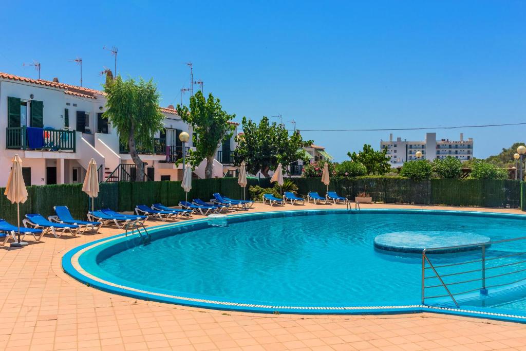 une grande piscine avec des chaises et des parasols dans l'établissement Lurdes, à Ciutadella