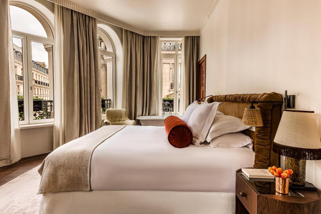 Schlafzimmer mit einem großen weißen Bett und Fenstern in der Unterkunft Château des Fleurs - Hôtel & Spa - Paris Champs-Elysées in Paris