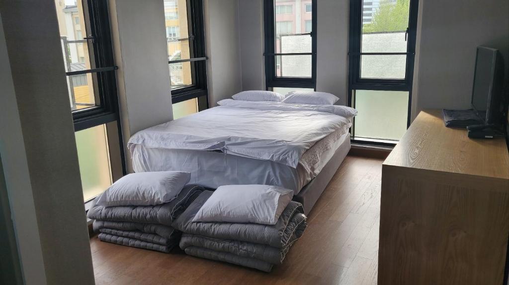 a large bed with pillows and a chair in a room with windows at J.Hill House in Seoul