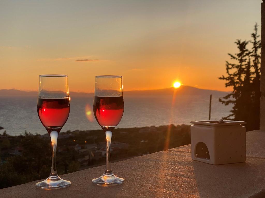 dos copas de vino sentadas en una mesa con la puesta de sol en Horizon Villa Mani - Seaview Family Friendly House, en Stoupa