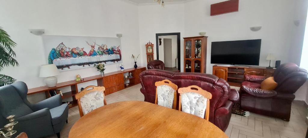 a living room with a table and chairs and a television at City center apartment in Sopron