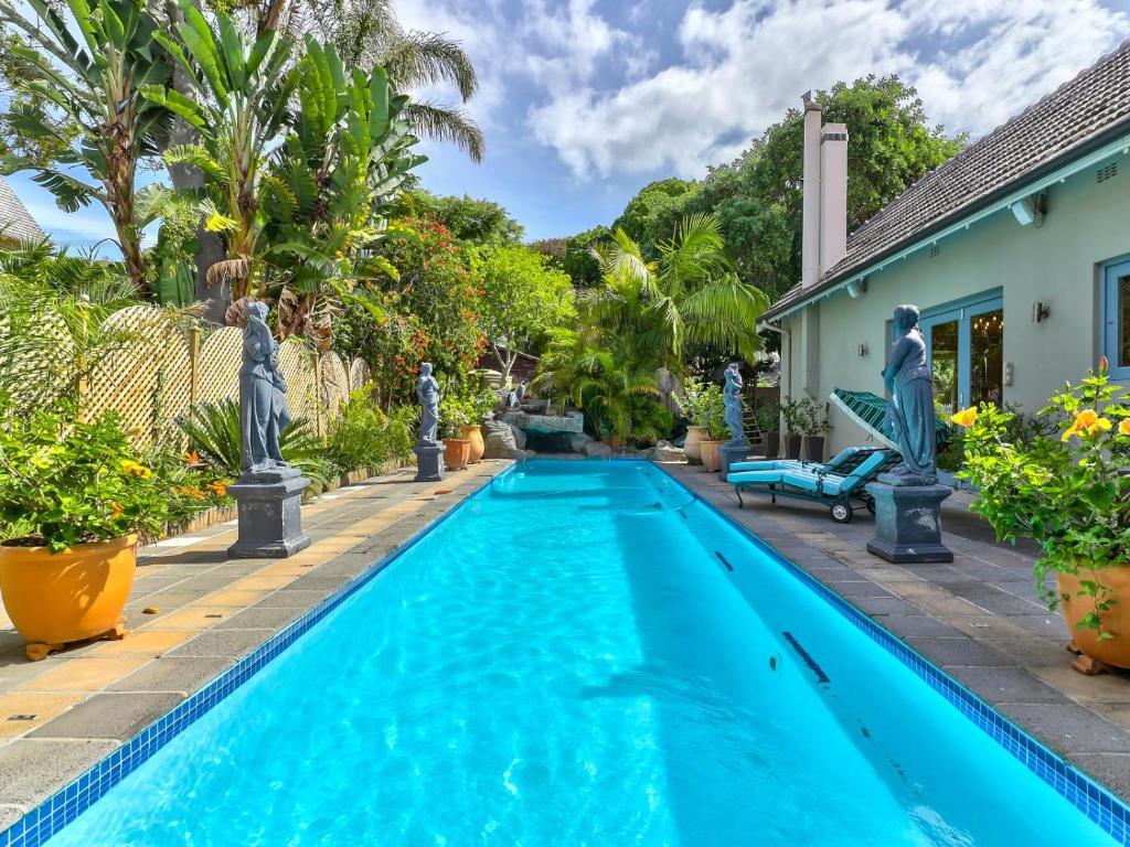una piscina en el patio trasero de una casa con palmeras en Villa Jesdene, en Ciudad del Cabo