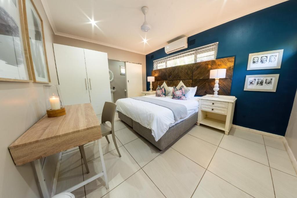 a bedroom with a bed and a table and a desk at Faraway Lodge in Durban