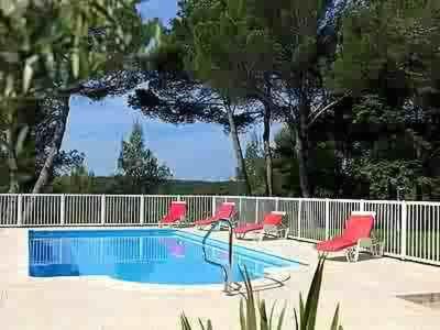 une piscine avec des chaises rouges et une clôture dans l'établissement Hôtel Le Valaurie, à Saint-Nazaire