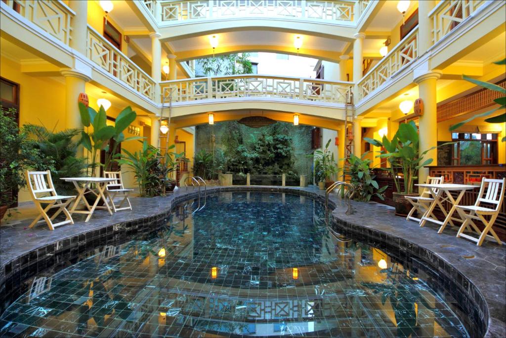 an indoor pool in a hotel with tables and chairs at Thanh Van 1 Hotel in Hoi An