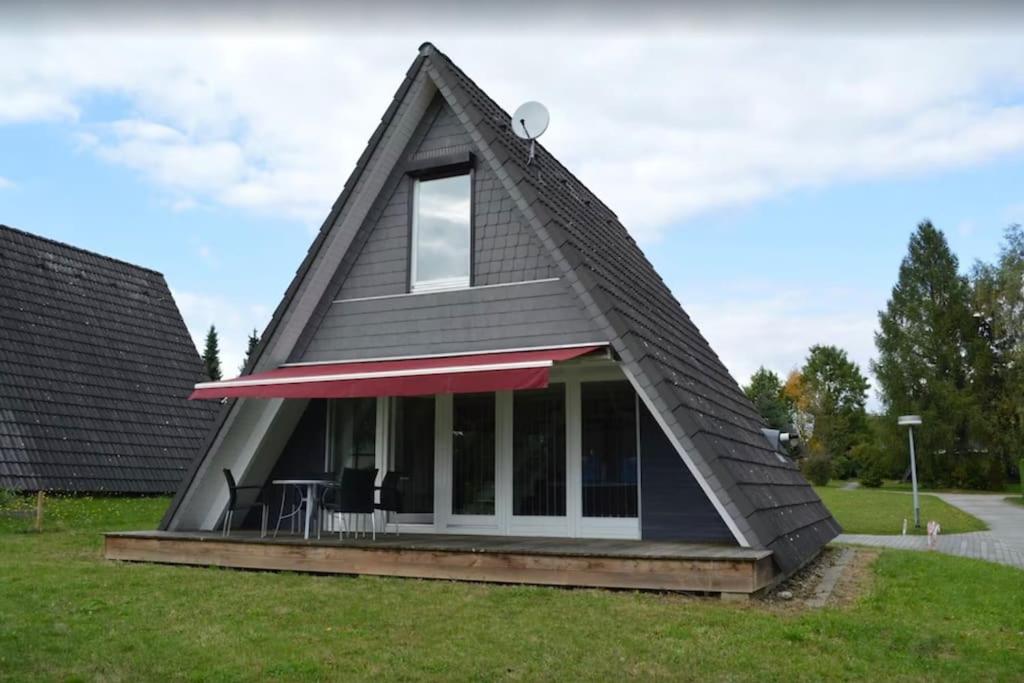 uma casa com um telhado de gambrel com um alpendre em Ferienhaus in Waldkatzenbach modern & renoviert em Waldbrunn