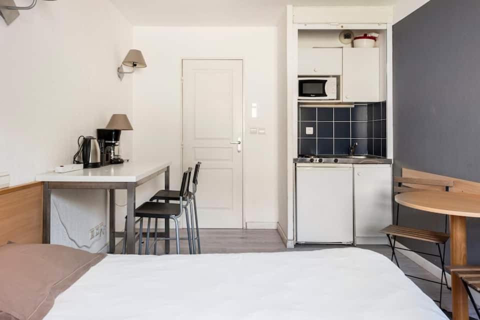 Un dormitorio con una cama y una cocina con una mesa. en Marseille Prado Perier, en Marsella