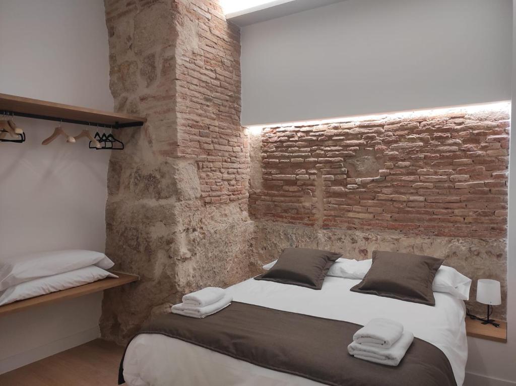 a bedroom with a bed and a brick wall at Costanilla Turismo in Zamora