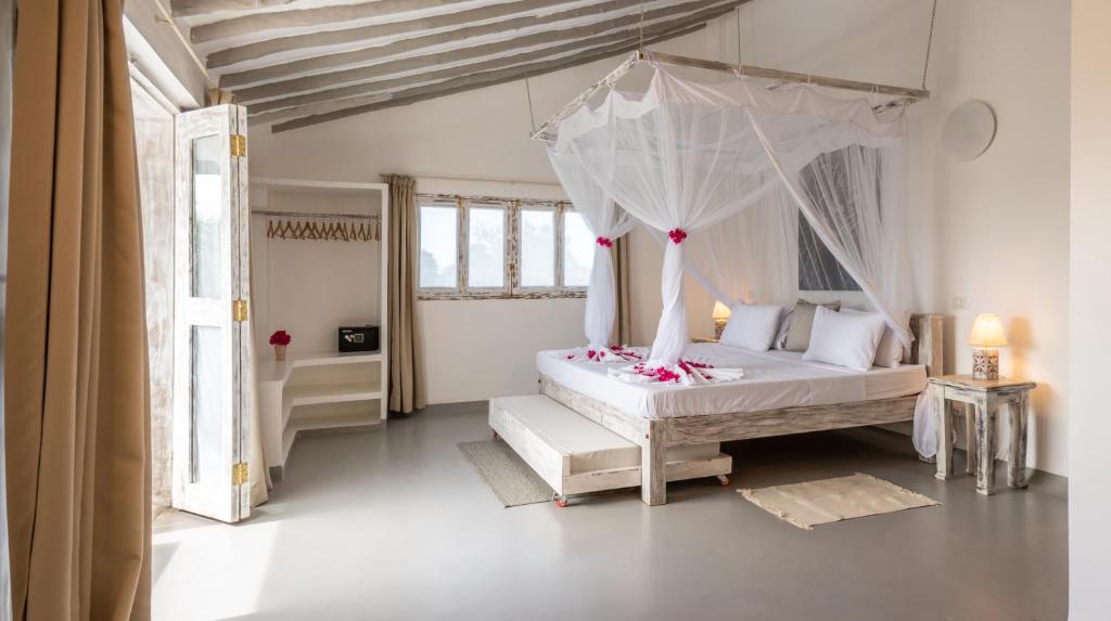 ein Schlafzimmer mit einem weißen Bett mit Baldachin in der Unterkunft Casamia Suites in Diani Beach