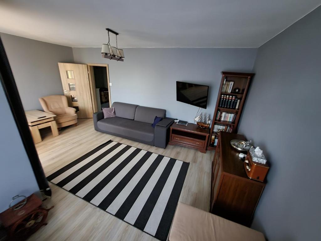 een woonkamer met een bank en een televisie bij Apartament Julia Łeba in Łeba