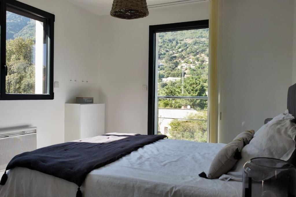 een slaapkamer met een bed en een groot raam bij Villa Cavalaire luxueuse & calme avec piscine in Cavalaire-sur-Mer