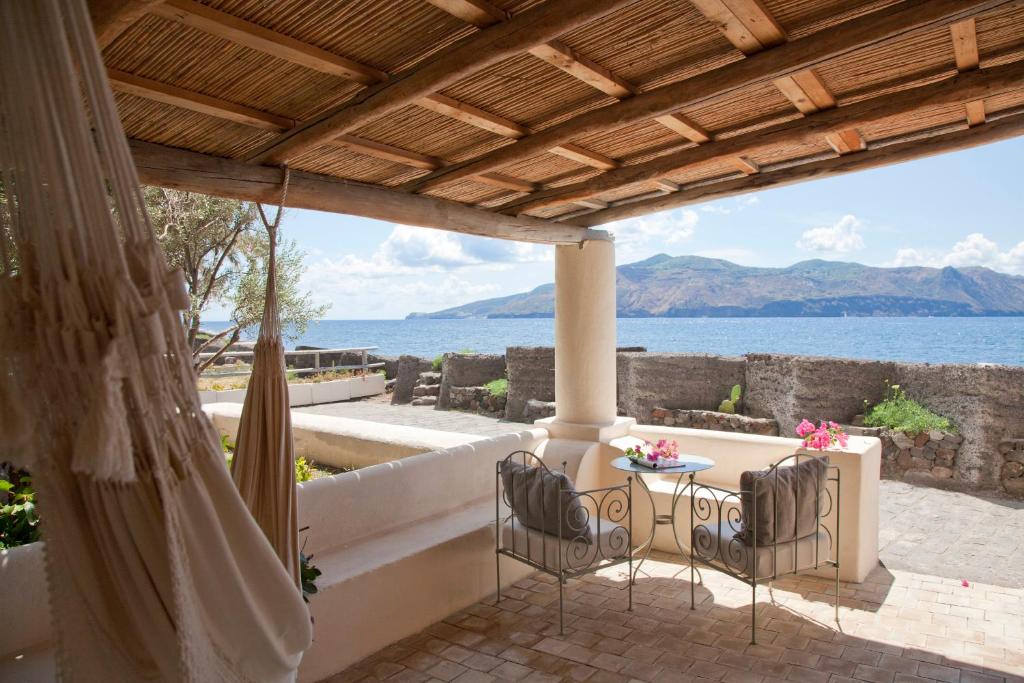 een patio met een tafel en stoelen en uitzicht op het water bij La Salina Hotel Borgo Di Mare in Lingua