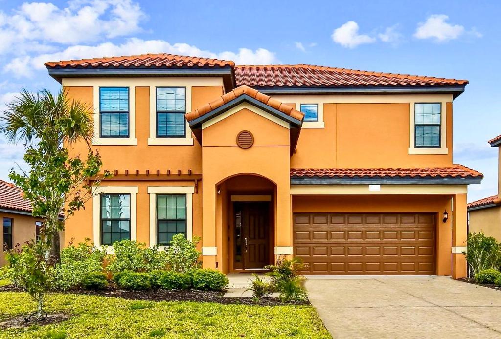 a large orange house with a garage at Large family friendly Vacation Home, Private Pool, Golf course location, Nr Orlando Disney Parks Florida in Davenport