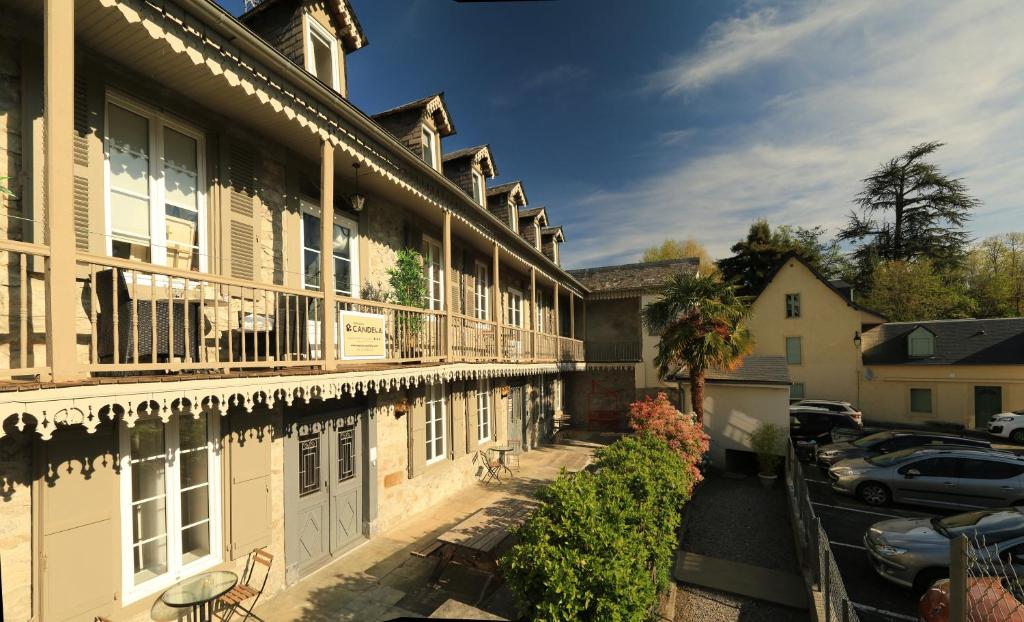 a building with a balcony and a parking lot at Maison Candela in Argelès-Gazost