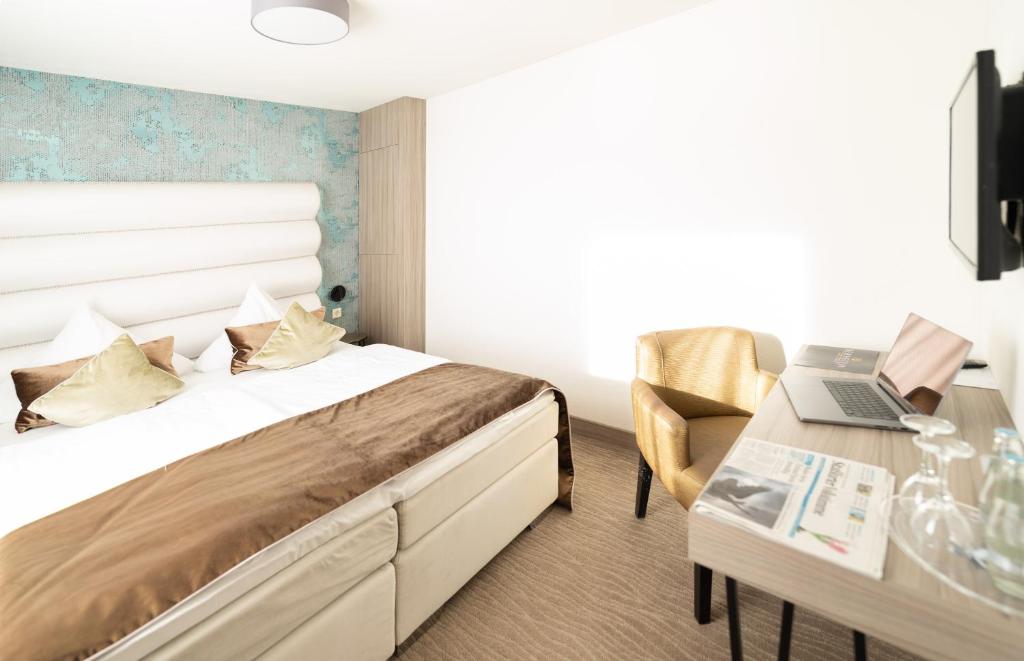 ein Schlafzimmer mit einem Bett und einem Schreibtisch mit einem Laptop in der Unterkunft Bernstein Salzlandcenter in Staßfurt
