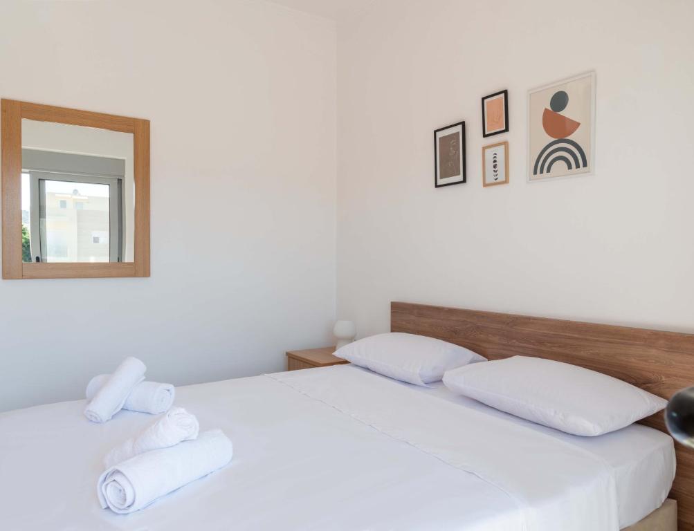 1 dormitorio con 1 cama con sábanas blancas y espejo en Apartment Santa Marina 6, en Asgourou