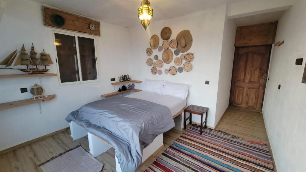 a bedroom with a bed and a window and a door at EL Faro Surfstay in Tamri