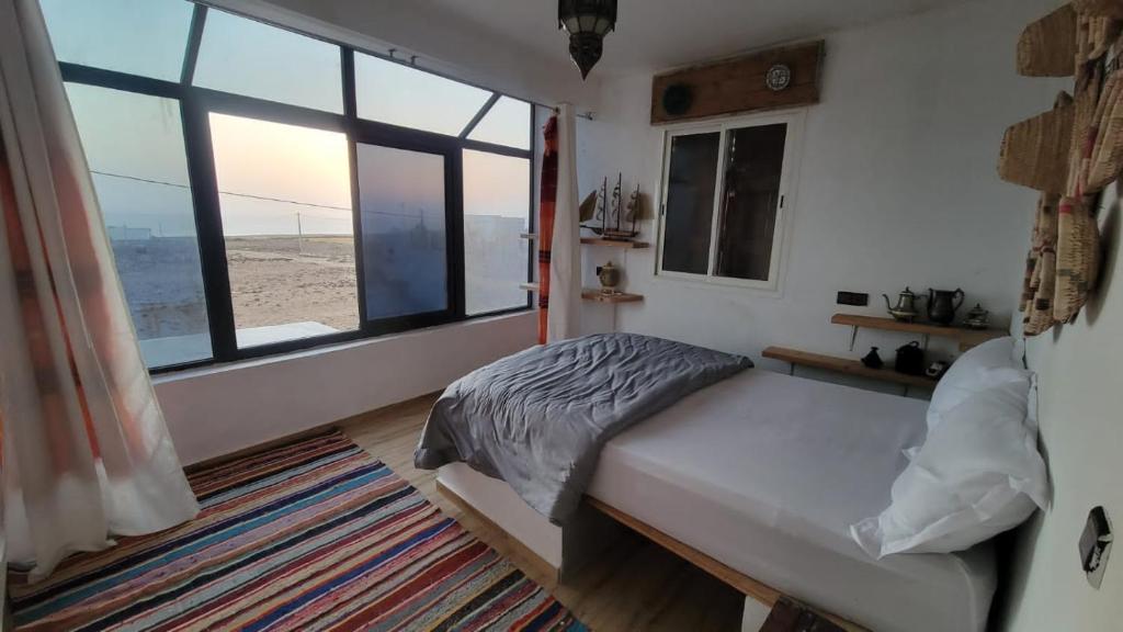 a bedroom with a bed and a large window at EL Faro Surfstay in Tamri